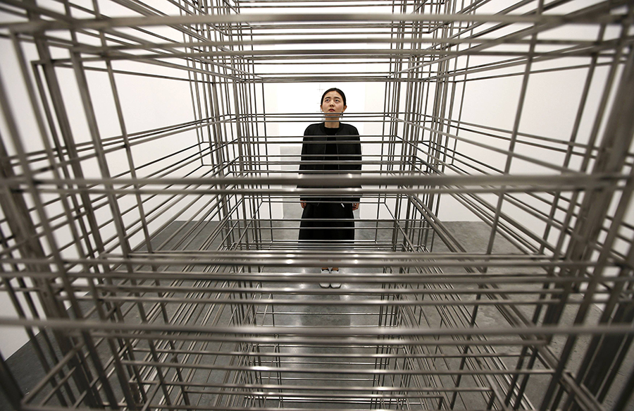 A member of the gallery poses for a photograph next to a piece called "Fit", by artist Antony Gormley, which forms part of an exhibition entitled "Fit", at the White Cube gallery in London, Britain September 29, 2016.   REUTERS/Peter Nicholls